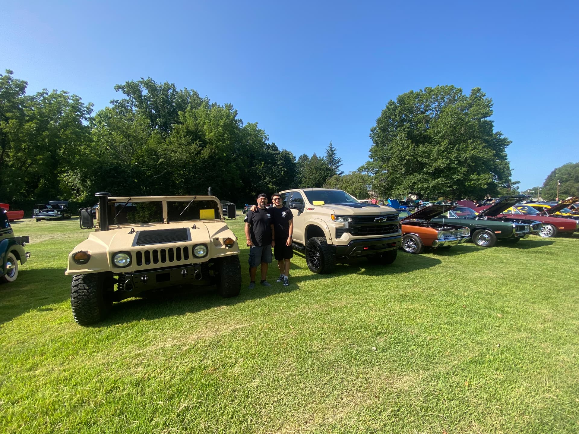 SG Automotive team standing between their Humvee and Silverado at a Burlington County car show